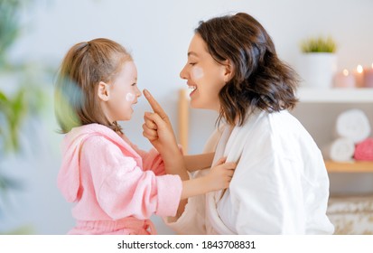 Happy Family! Mother And Daughter Child Girl Are Caring For Skin In The Bathroom.