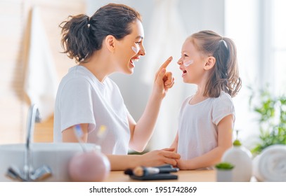 Happy Family! Mother And Daughter Child Girl Are Caring For Skin In The Bathroom.