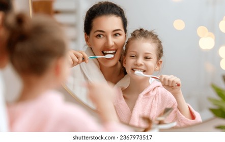 ¡Feliz familia! Madre e hija están cepillando dientes en el baño.