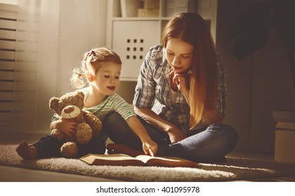 Happy Family Mother And Daughter Read A Book In The Evening At Home