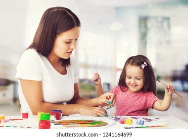 Happy family mother and daughter together paint. Woman helps child girl. - Shutterstock ID 1241164699