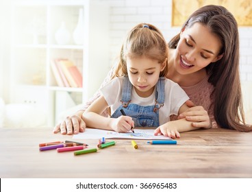 Happy family. Mother and daughter together paint. Adult woman helps the child girl.
