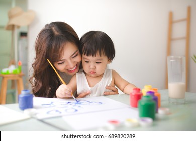 Happy family mother   daughter together paint  Asian woman helps her child girl 