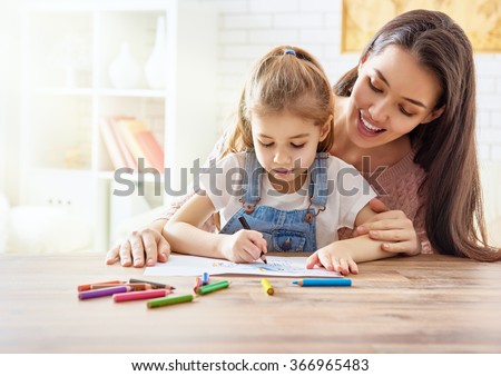 Happy family. Mother and daughter together paint. Adult woman helps the child girl.