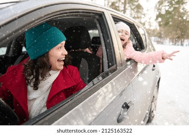 Happy Family, Mother And Daughter In Warm Clothes Travel By Car On A Beautiful Cold Snowy Day. Adorable Cheerful Child, Little Girl Catching Snowflakes Falling On Her Hand. Enjoy Winter Holiday