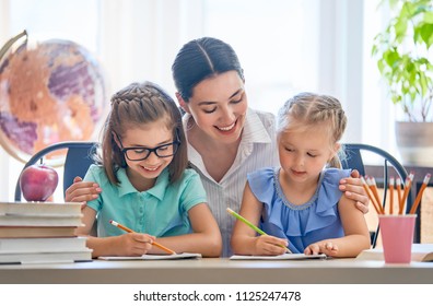 Happy family. Mother and daughters are learning to write. Adult woman teaching children the alphabet.
