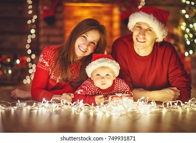 Happy Family Mother Father And Baby At Christmas Tree  At Home