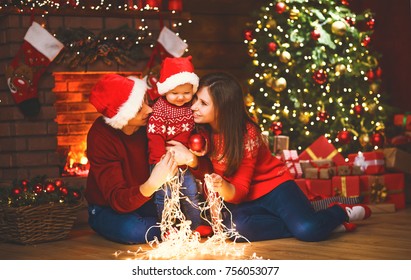 Happy Family Mother Father And Baby At Christmas Tree  At Home