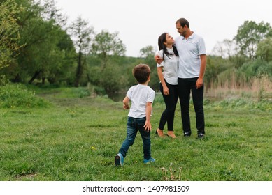 Happy family: mother father and child son on nature on sunset. Mom, Dad and kid laughing and hugging, enjoying nature outside. Sunny day, good mood. concept of a happy family