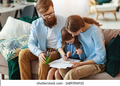 Happy Family Mother Father And Child Daughter Draw  At Home On The Couch
