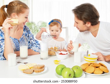 Happy family mother, father, child baby daughter having breakfast at home