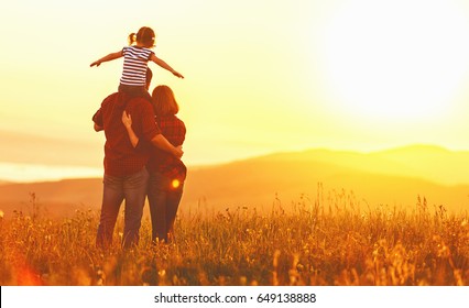 Happy family: mother father and child daughter on nature  on sunset