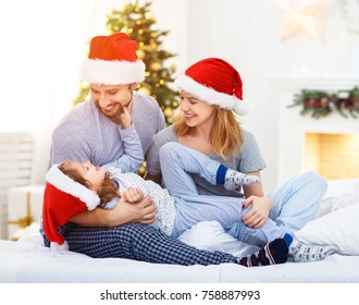 Happy Family Mother Father And Child On Christmas Morning In Bed In Pajamas Open Gifts
