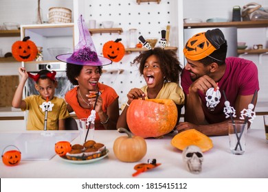 Fröhlicher Familienvater und Kinder bereiten sich auf Halloween vor. Sie schnitzen Kürbis.