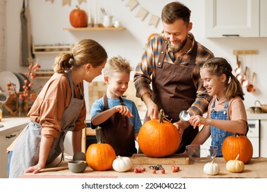 Happy family mother, father  and children daughter and son to remove   pulp from pumpkin while carving jack o lantern with family in cozy kitchen at home, parents with kids preparing for Halloween - Shutterstock ID 2204040221