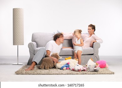 Happy Family, Mother, Father And Daughter, Mom And Dad Playing With His Daughter On The Carpet In The Living Room