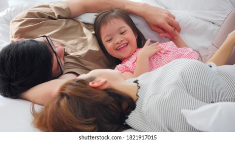 Fröhliche Familie mit Mutter, Vater und behinderter Tochter verbringen Zeit zusammen im Schlafzimmer.