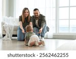 Happy family. Mother father looking at cute little toddler girl crawling on floor in bedroom. Infant baby resting playing with parents indoor at home. Mom dad newborn baby. Cute crawling child