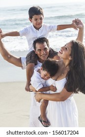 A Happy Family Of Mother, Father Parents & Two Boy Son Children, Playng And Having Fun In The Waves Of A Sunny Beach