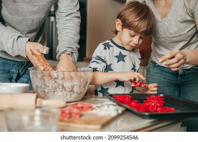 Happy Family Mother, Father And Son Baking Christmas Cookies On Cozy Kitchen At Home, Mixing Dough, Little Boy Is Helping Mom And Dad In Making Cookies. Winter Holiday Spirit. Spending Time Together 