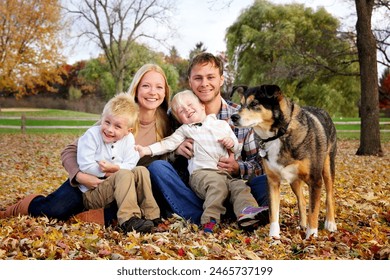 A happy family of a mother, father, their 2 kids and their German Shepherd dog a smiling for a portrait under the fall trees on an Autumn day. - Powered by Shutterstock