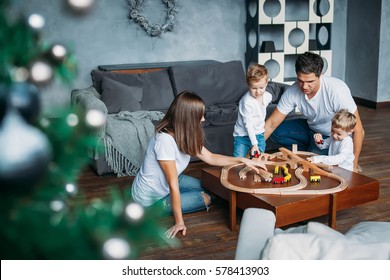 Happy Family Mother Father Twins Boys Playing With Toy Railway Road At Home On Table Christmas