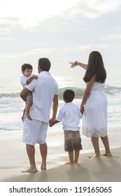 A Happy Family Of Mother, Father And Two Children, Two Boy Sons, Walking And Having Fun In The Sand On A Sunny Beach