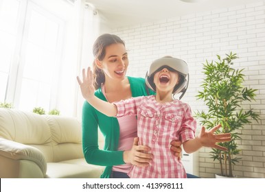 Happy family! Mother and her child daughter play game in virtual reality glasses. - Powered by Shutterstock