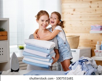 Happy Family Mother Housewife And Child Daughter  Ironing Clothes Iron In Laundry At Home
