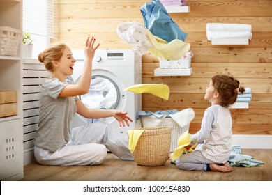 Happy family mother housewife and child daughter in laundry with washing machine 