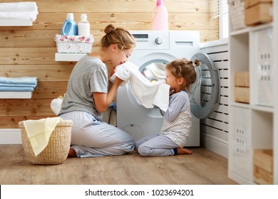 Happy family mother housewife and child daughter in laundry with washing machine 