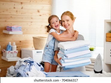 Happy Family Mother Housewife And Child Daughter  Ironing Clothes Iron In Laundry At Home