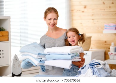 Happy Family Mother Housewife And Child Daughter  Ironing Clothes Iron In Laundry At Home
