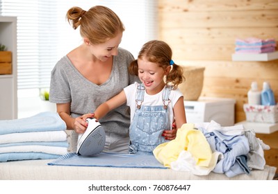 Happy Family Mother Housewife And Child Daughter  Ironing Clothes Iron In Laundry At Home
