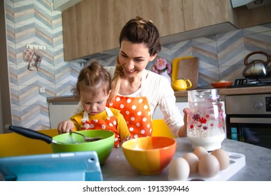 Happy family , mother and kid cooking in the morning at home the sweet biscuit with fun. Two people make the dough on the kitchen. Woman helps to child