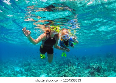 Happy family - mother, kid in snorkeling mask dive underwater with tropical fishes in coral reef sea pool. Show by hands divers sign OK. Travel lifestyle, beach adventure on summer holiday with child.