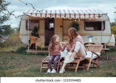 Happy family - mother and little daughter relaxing and having fun in countryside on camper van vacation 