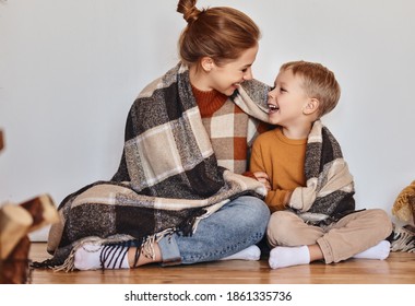 Happy Family Mother And Loving Son Hug And Laugh Wrapped In A Warm Blanket On A Cozy Winter Evening At Home 
