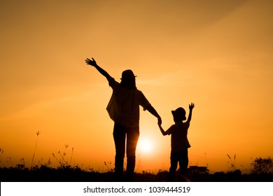 Happy Family. A Mother And Son Playing In Grass Fields Outdoors At Evening Silhouette.Vintage Tone And Copy Space