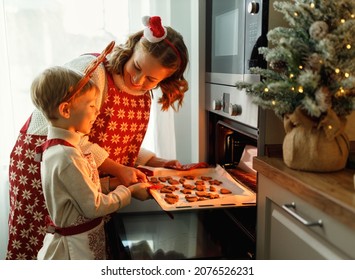 Happy family mother and son taking freshly baked Christmas cookies from oven while cooking together in cozy kitchen during winter holidays, little boy helping mom to prepare for New Year at home - Powered by Shutterstock