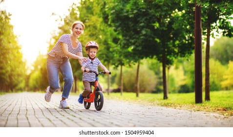 Happy Family Mother Teaches Child Son To Ride A Bike In The Park In Nature
