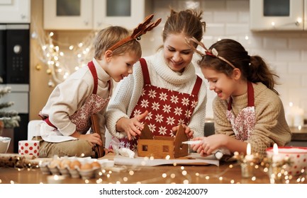 Happy family mother and two kids in xmas aprons decorating Christmas honey gingerbread house together, mom with children enjoying cooking in cozy kitchen at home during winter holidays - Powered by Shutterstock