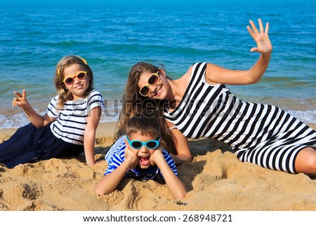 Happy family - mother and two kids, boy and girl, are playing and laughing on the beach