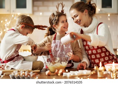 Happy Family Mother And Two Little Kids Making Christmas Homemade Cookies Together While Preparing For New Year At Home, Smiling Mom Making Dough With Children In Kitchen Decorated For Xmas