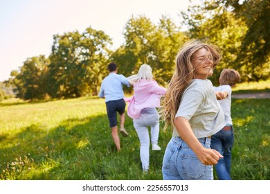 Happy family in motion on a green meadow in summer in nature - Shutterstock ID 2256557013