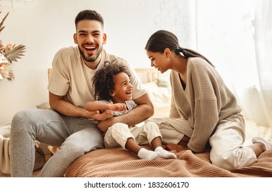 Happy Family Multi Ethnic Mother, Father And Son  Laughing, Playing,and Tickles In Bed In Bedroom At Home
