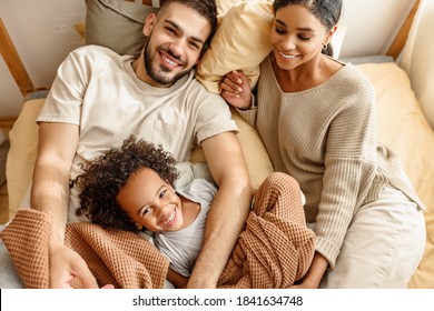 happy family multi ethnic mother, father and son  laughing, playing,and tickles in bed in bedroom at home
