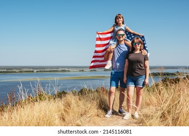 Happy family in nature with US American flag on a sunny day. Freedom and lifestyle concept.