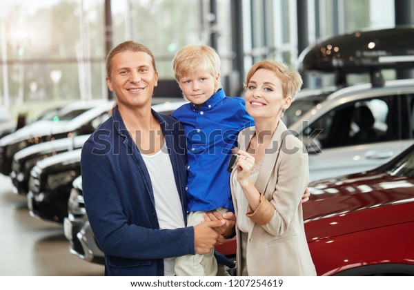 Happy family\
near new car. Auto dealership\
centre