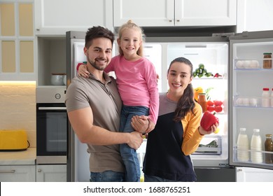 Happy Family Near Open Refrigerator In Kitchen